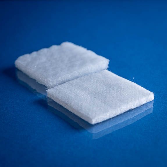 Type 2782 390gsm Washable Superabsorbent Needlepunch Nonwoven Fabric with top and bottom laminates. Shown dry and saturated on a blue background