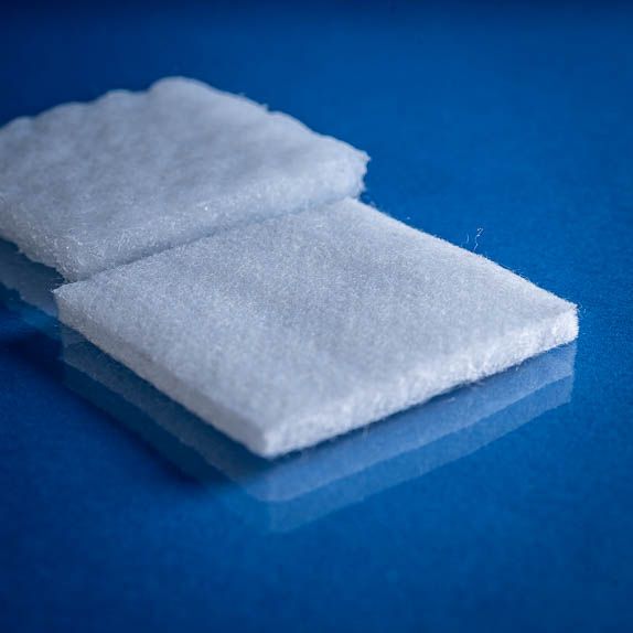 Type 2782 390gsm Washable Superabsorbent Needlepunch Nonwoven Fabric with top and bottom laminates. Shown close up dry and saturated on a blue background