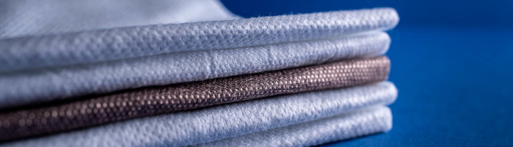 Technical Absorbents fabrics laid on top of each other on a blue background